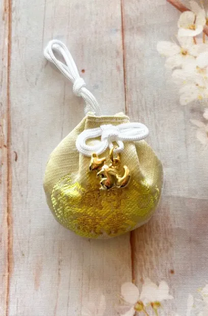 Omamori décoré avec un kitsune (renard) doré, symbole de la déesse Inari.